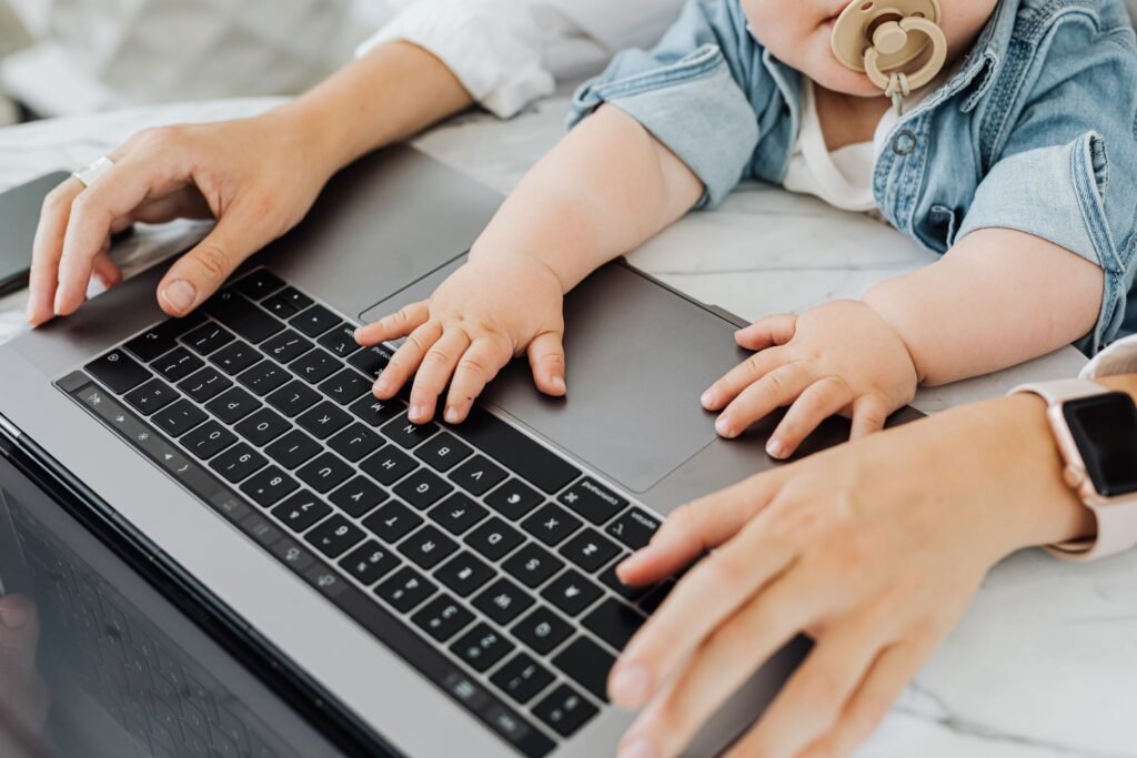 Renda extra em casa para mães: mulher trabalhando no notebook enquanto cuida do bebê