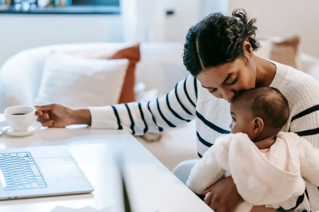 Renda extra em casa para mães: mulher trabalhando no notebook enquanto cuida do bebê